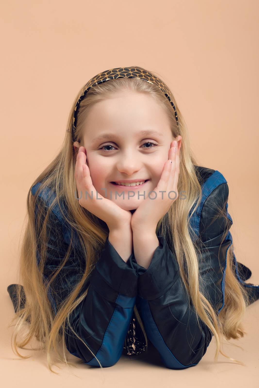 Portrait of fashion smiling european little long hair blonde girl posing in atelier