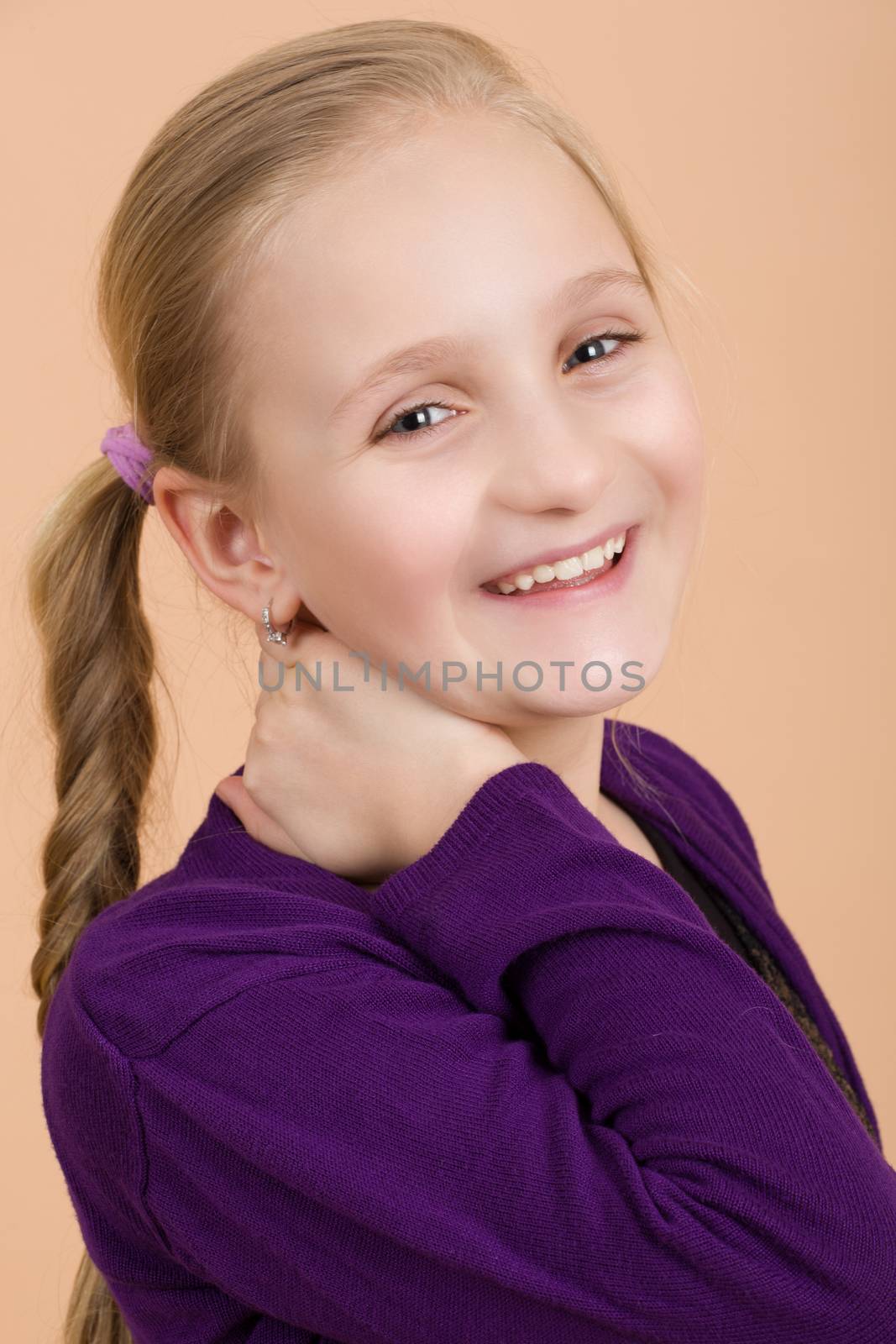 Portrait of fashion smiling european little long hair blonde girl posing in atelier