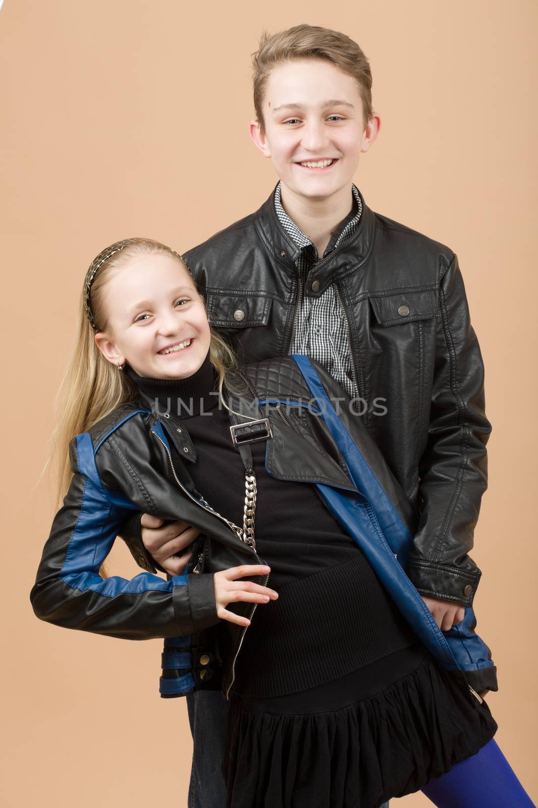 fashion smiling european little long hair blonde girl and her brother posing in atelier