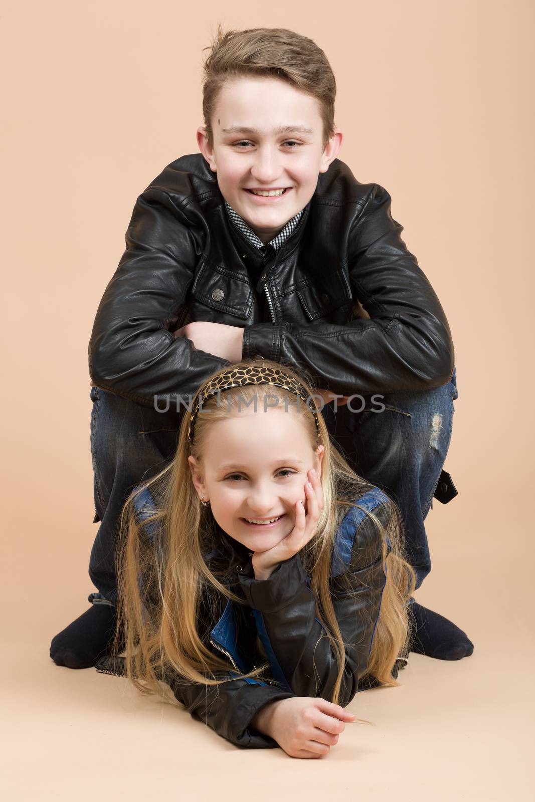 fashion smiling european little long hair blonde girl and her brother posing in atelier