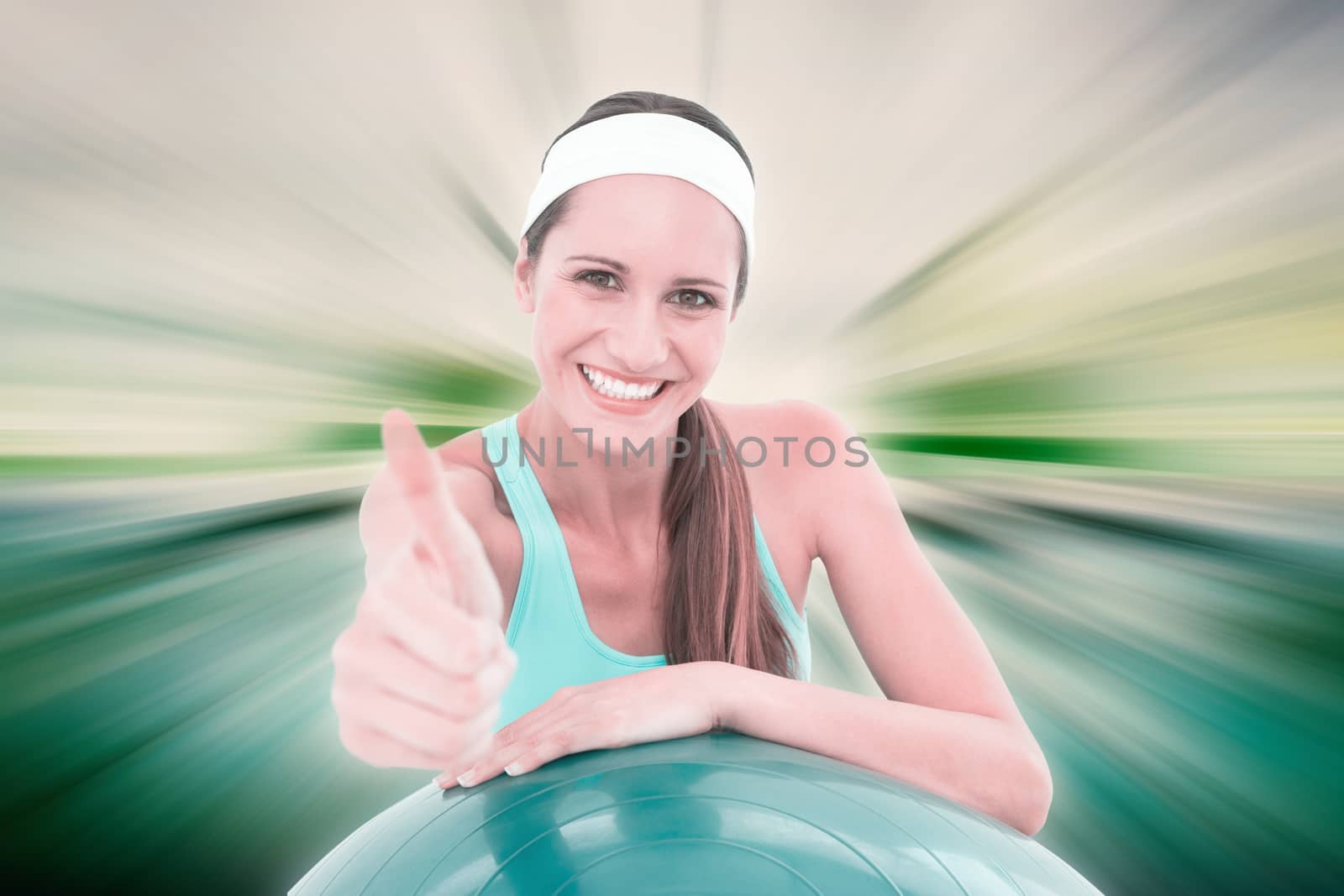 Smiling fit woman with fitness ball gesturing thumbs up against abstract background