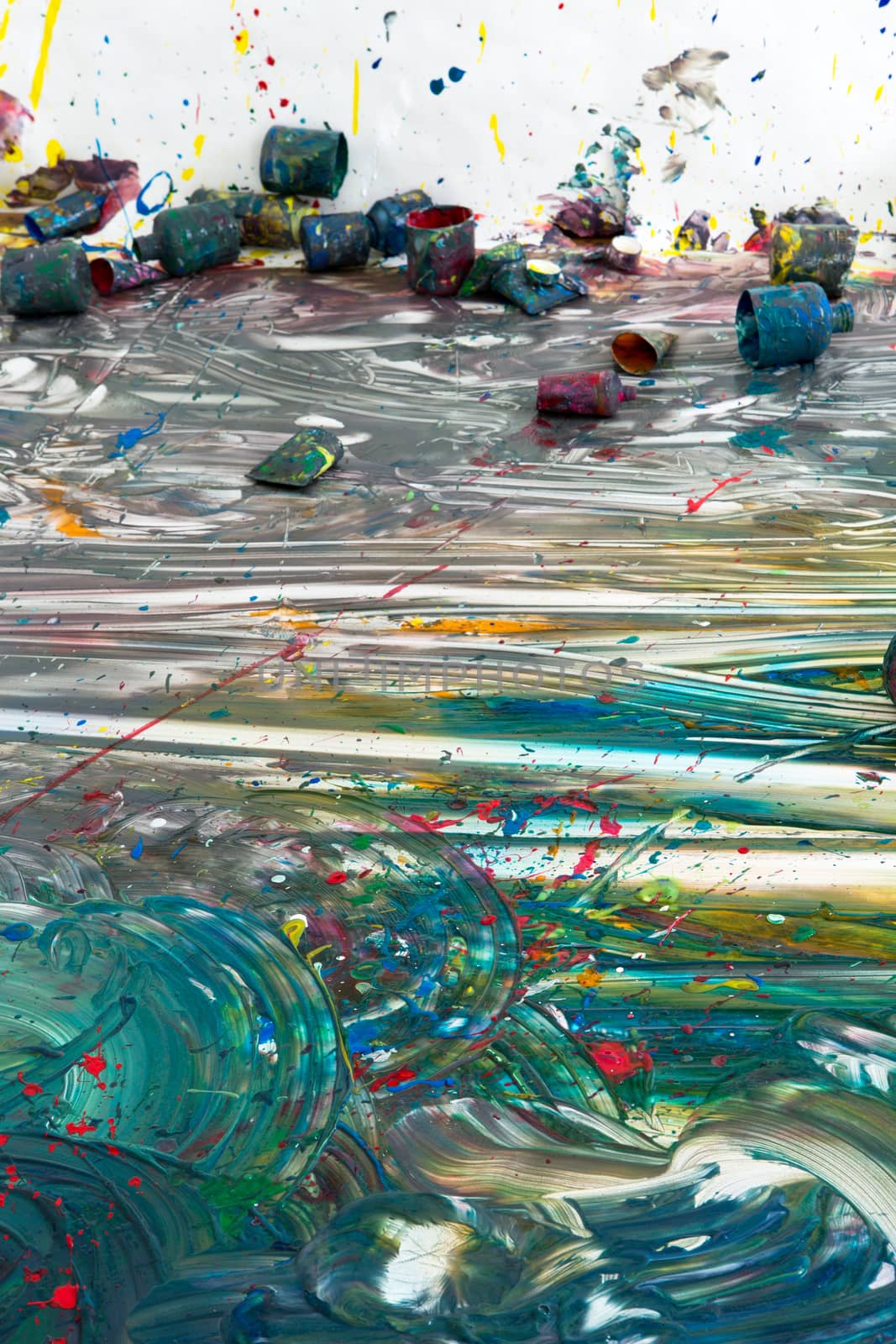 Colorful contemporary artwork on the floor with multiple discarded empty paint cans conceptual of creativity, inspiration and imagination