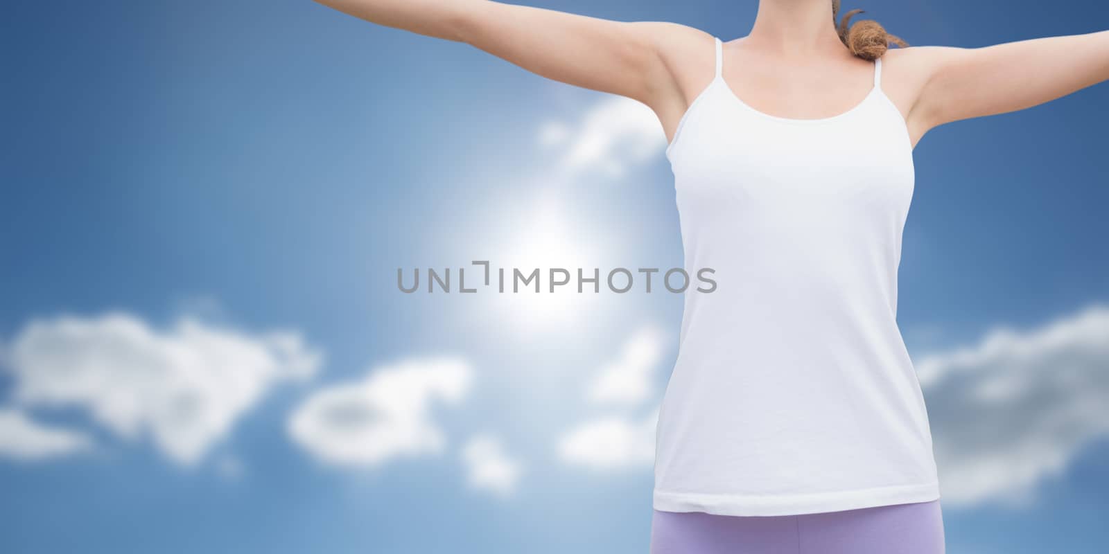 Woman standing with arms raised on countryside landscape against cloudy sky with sunshine