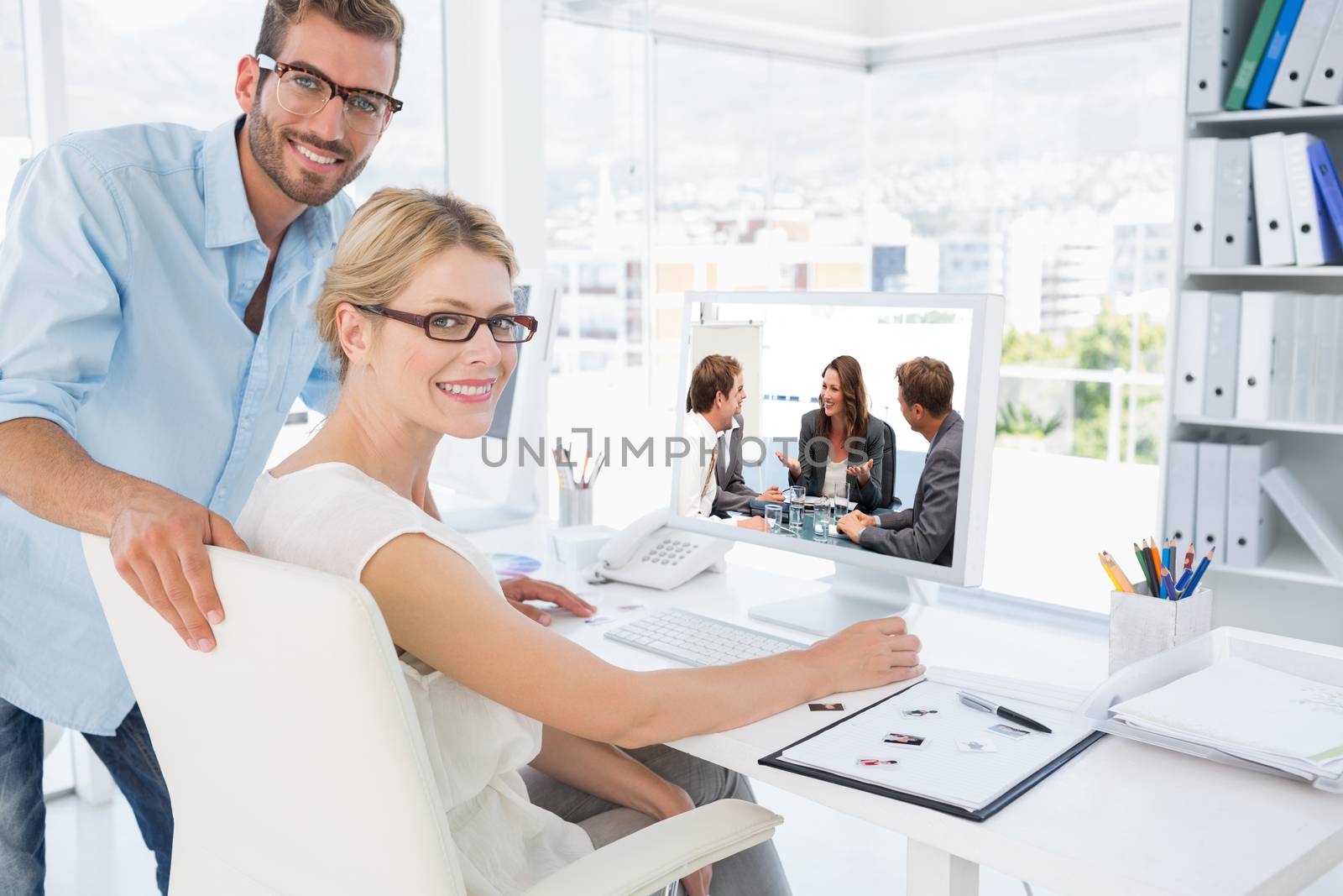 Attractive businesswoman laughing with her team against side view portrait of photo editors working on computer