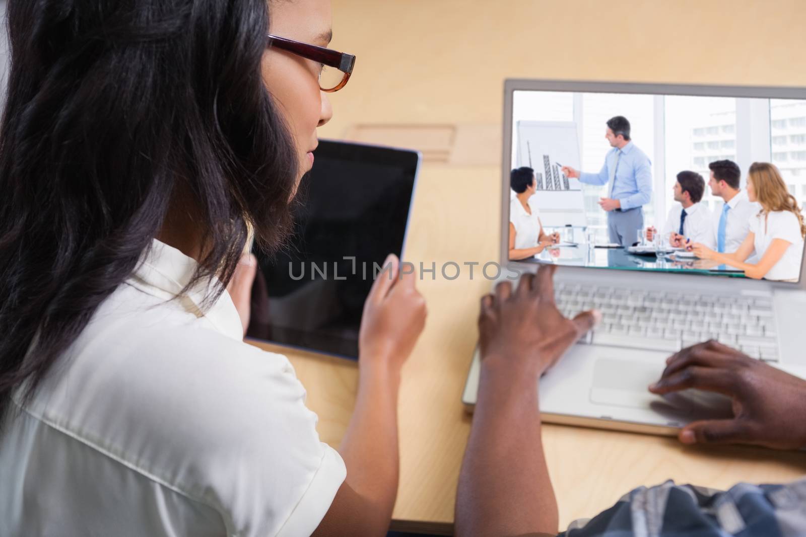 Business people in office at presentation against business people working on a laptop and a tablet