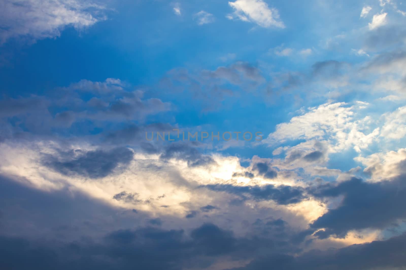Sun under clouds on blue sky background