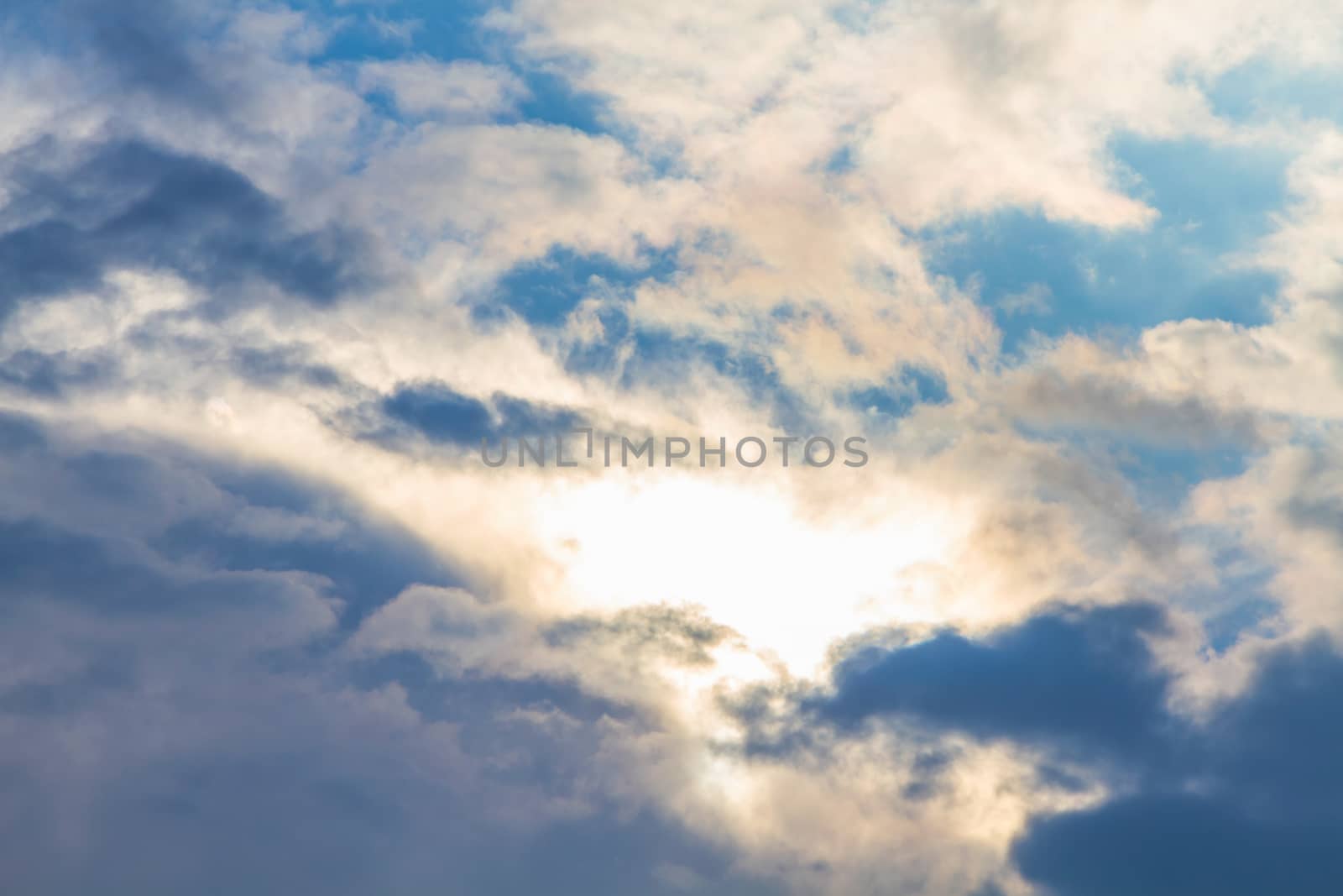 Sun under clouds on blue sky background