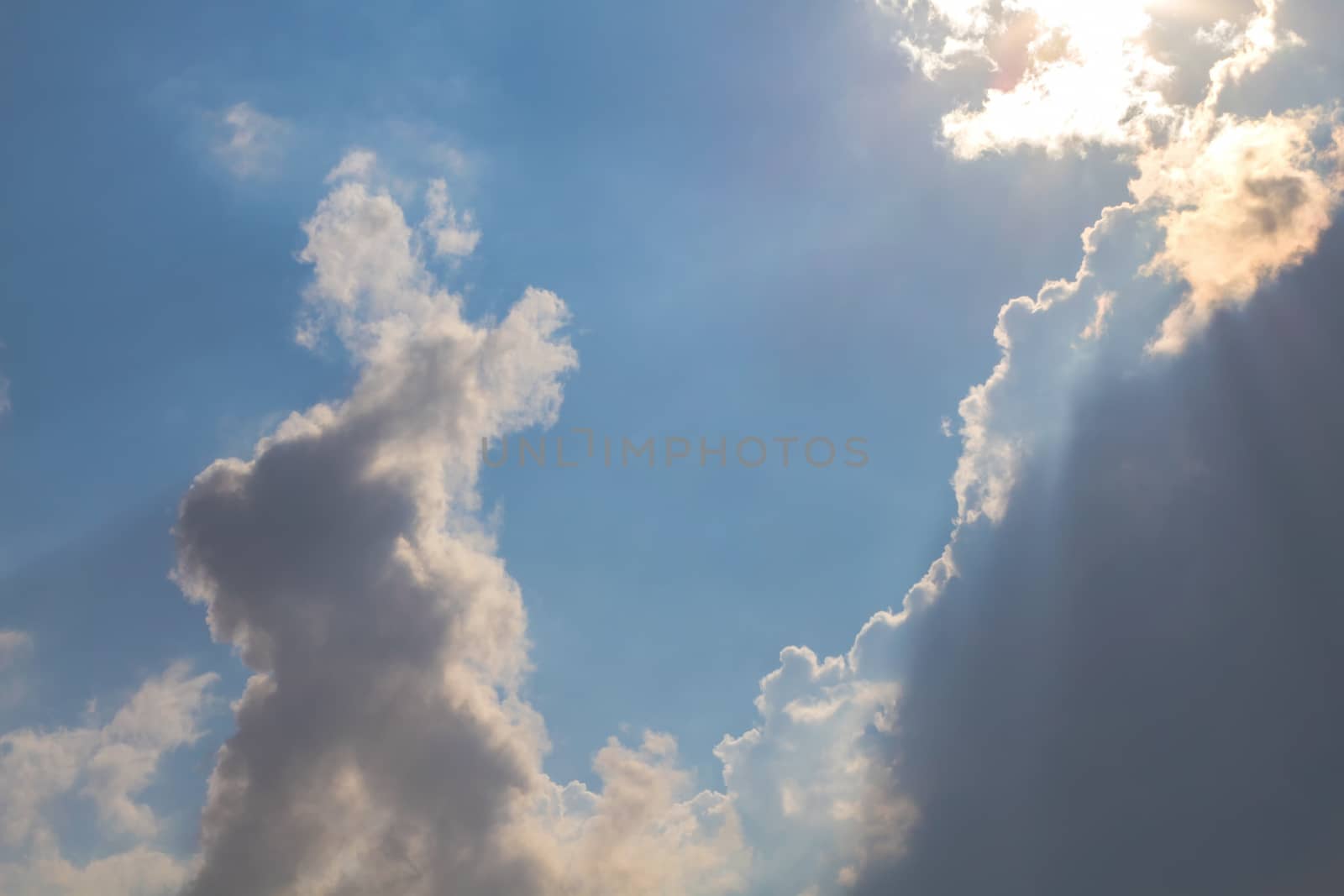 Sun under clouds on blue sky background