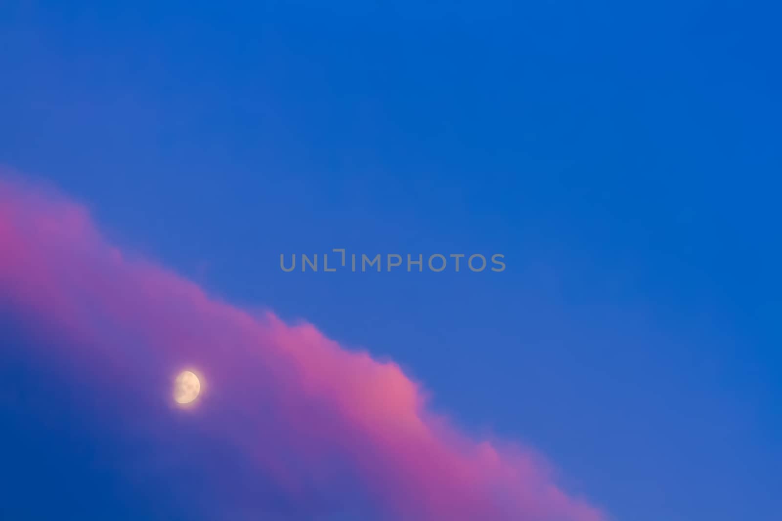 Moon under pink cloud on blue sky background
