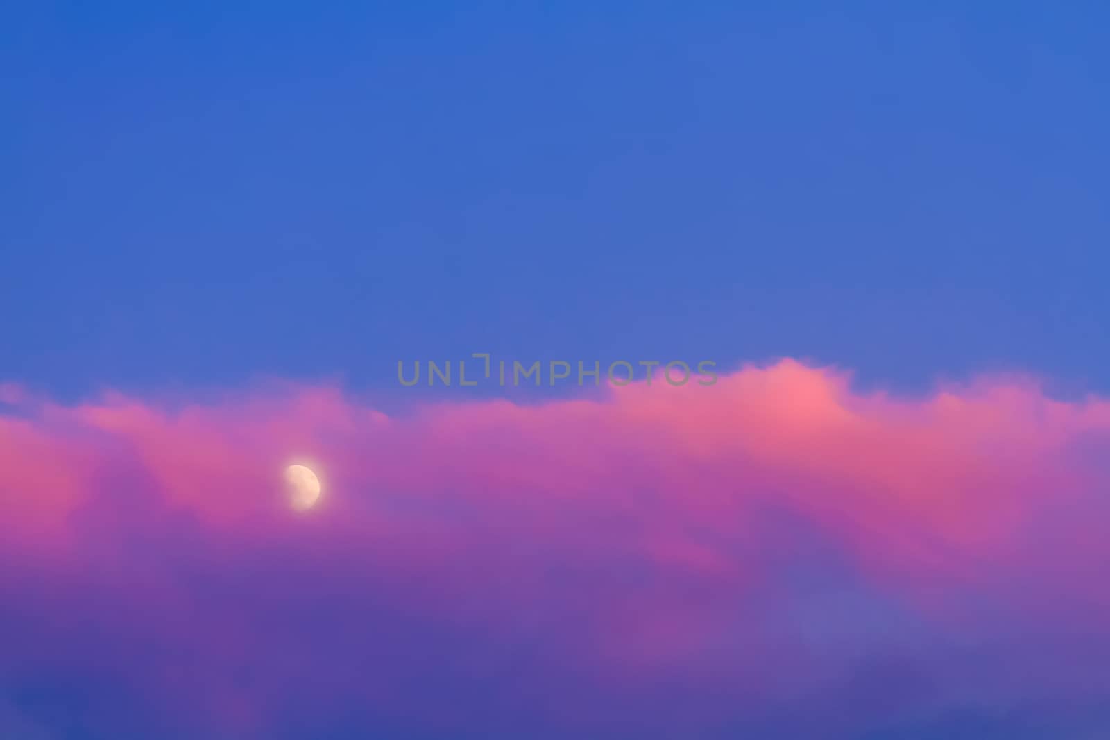 Moon under pink cloud on blue sky background