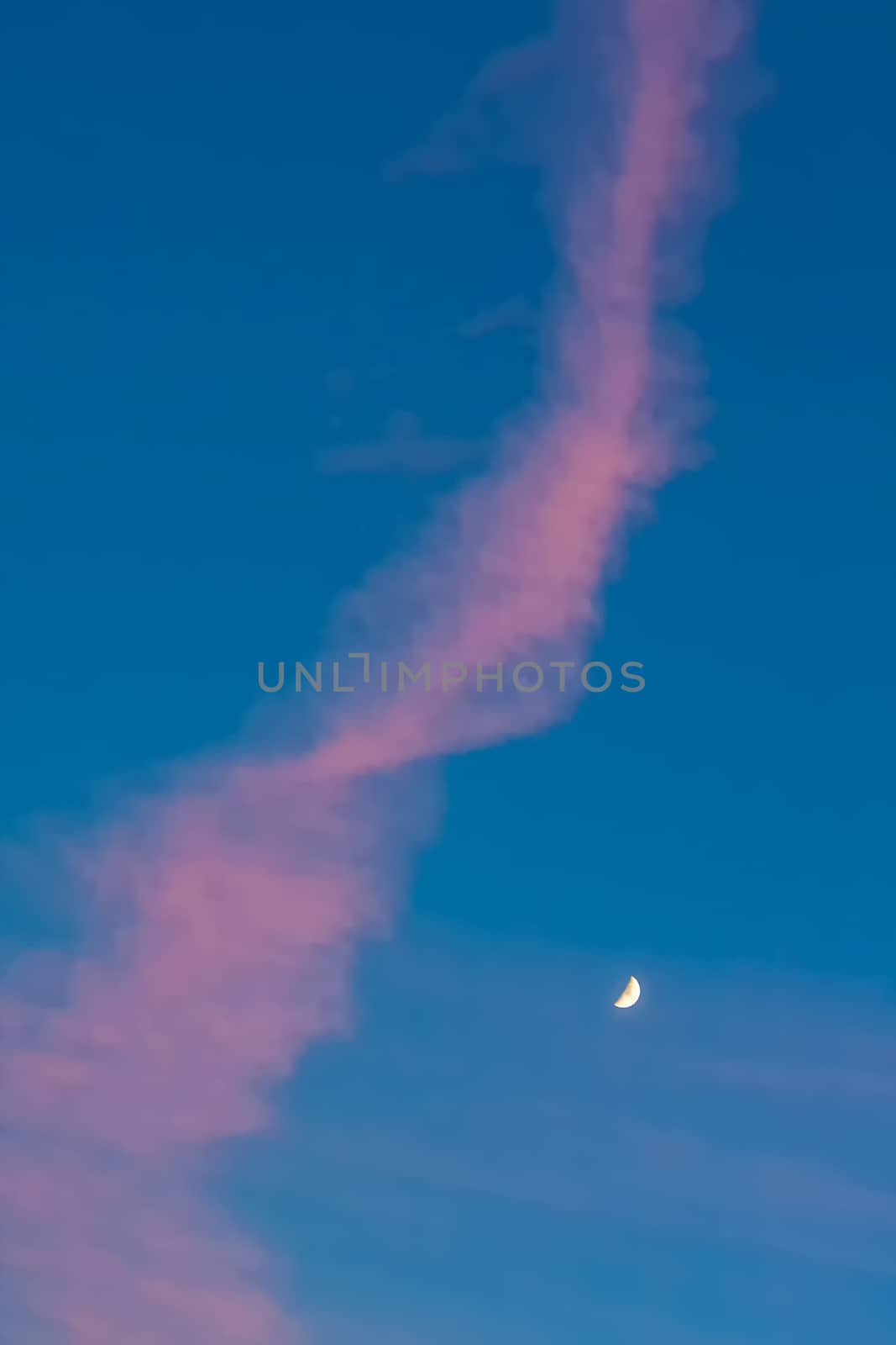Moon or crescent on blue sky background with pink clouds