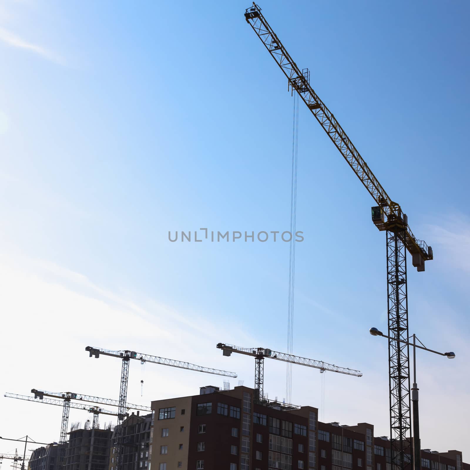 Construction cranes on building site on sky background