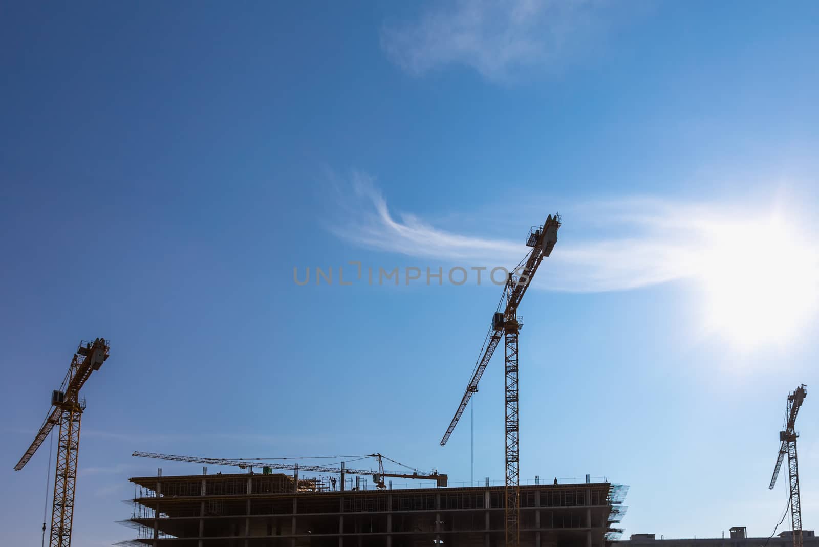 Construction cranes on building site on sky background