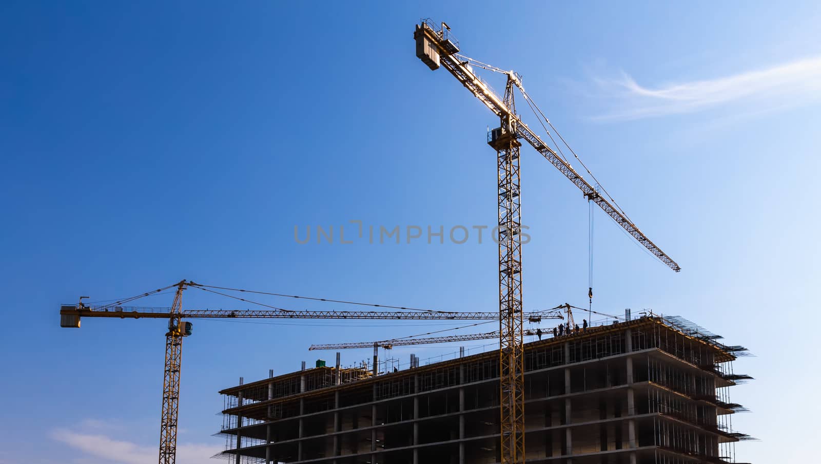 Construction cranes on building site on sky background
