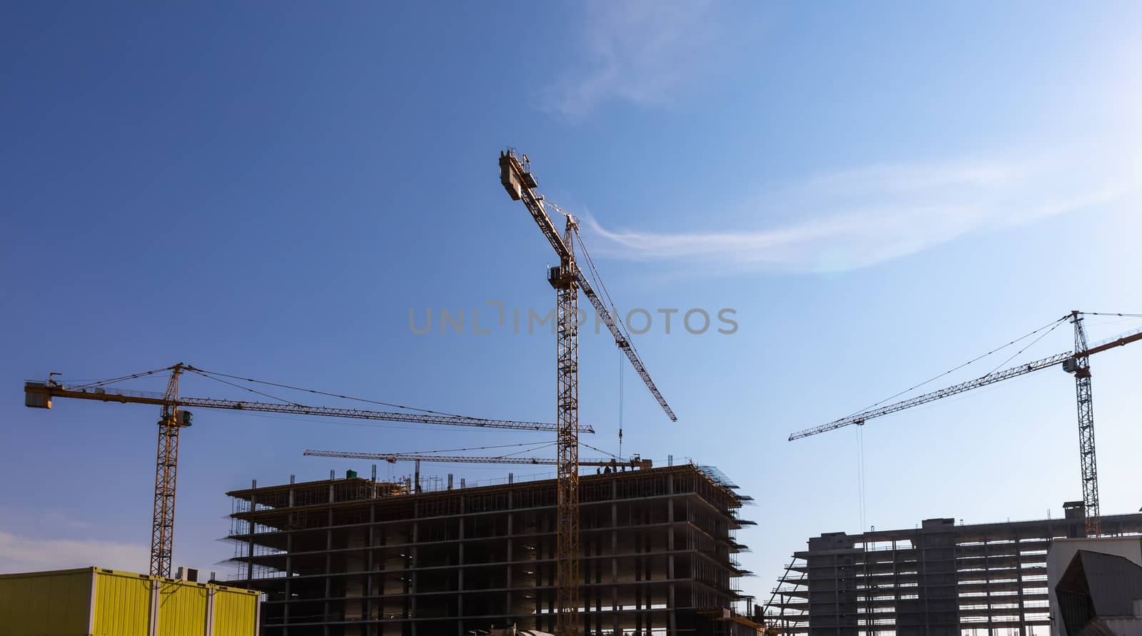 Construction cranes on building site on sky background