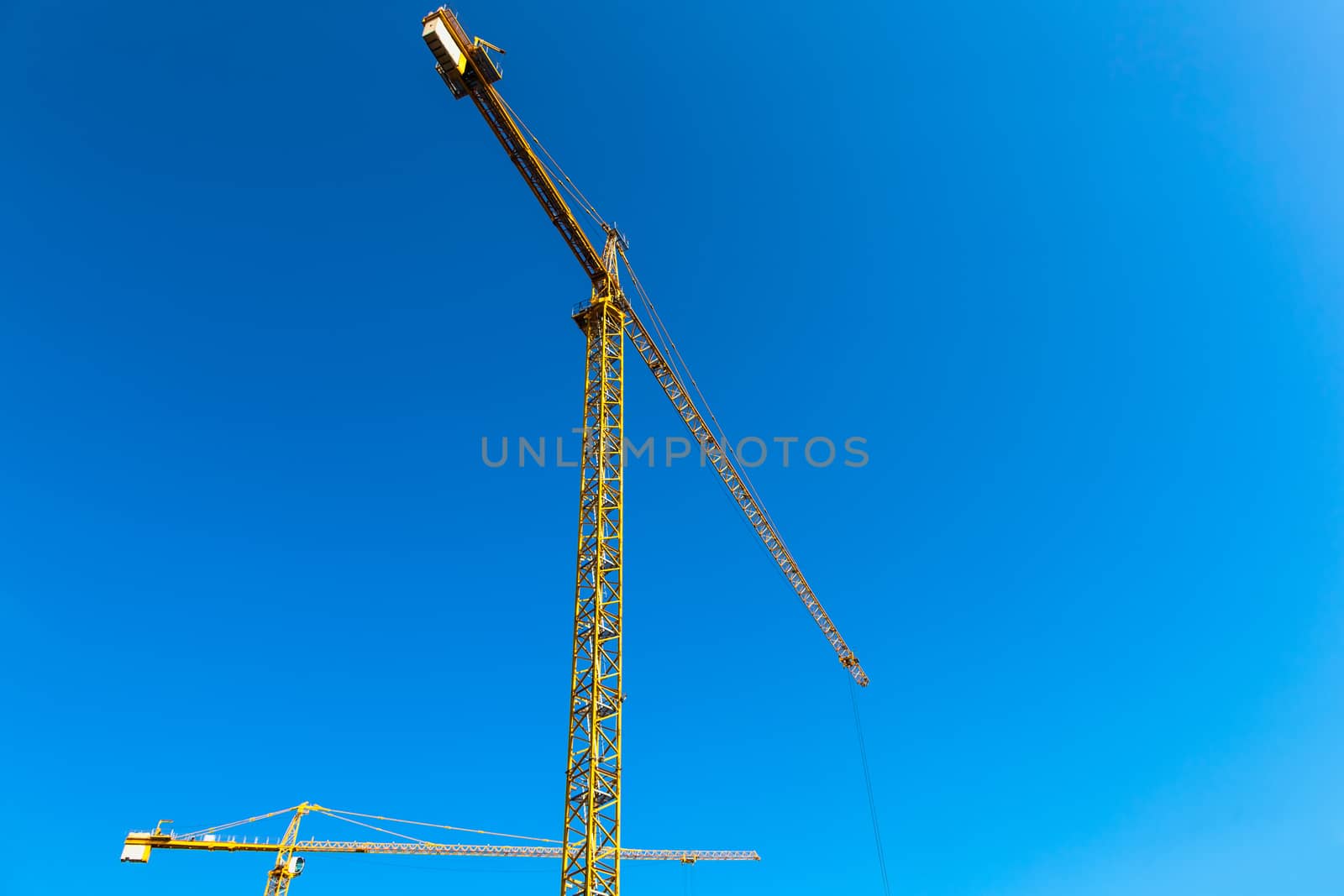 Construction cranes on blue sky background
