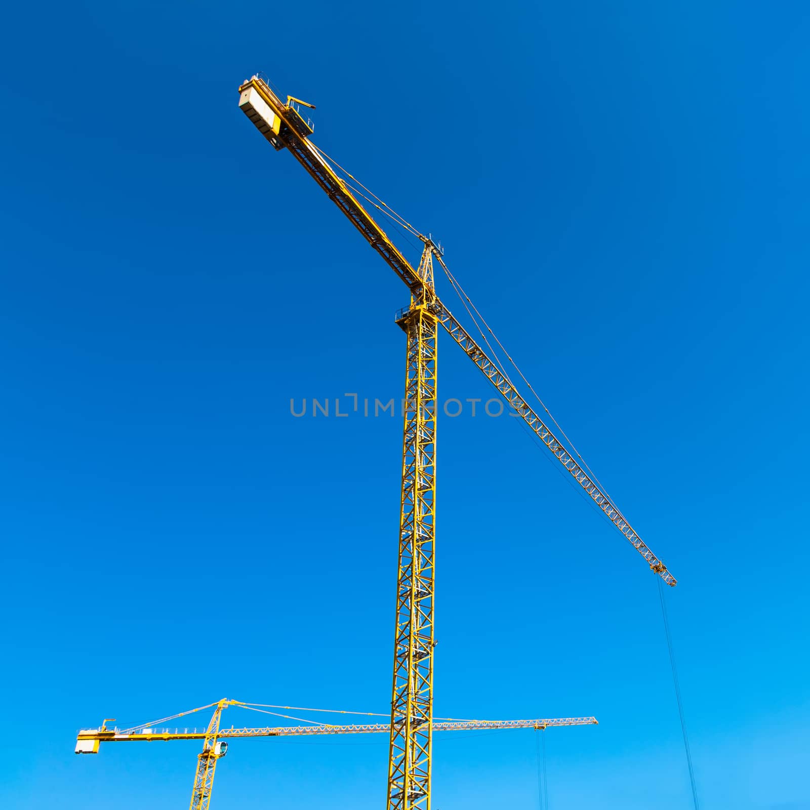 Construction cranes on blue sky background