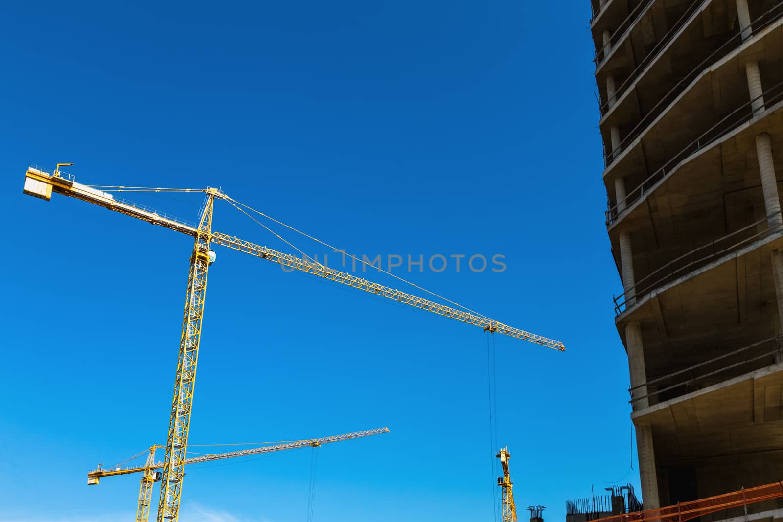 Construction cranes on building site on sky background
