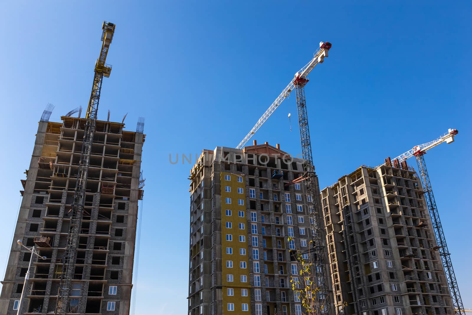 Construction cranes on building site on sky background