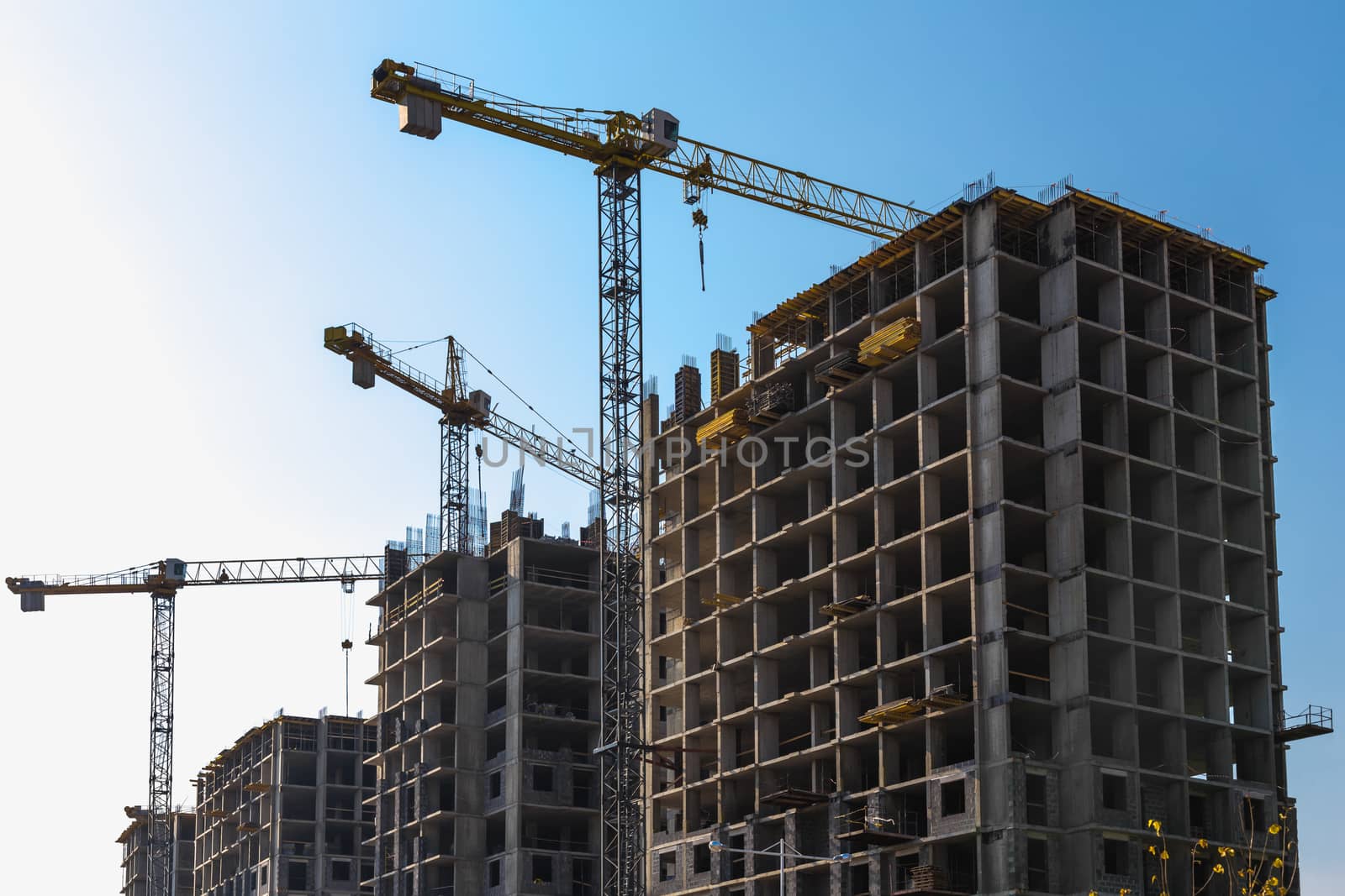 Construction cranes on building site on sky background