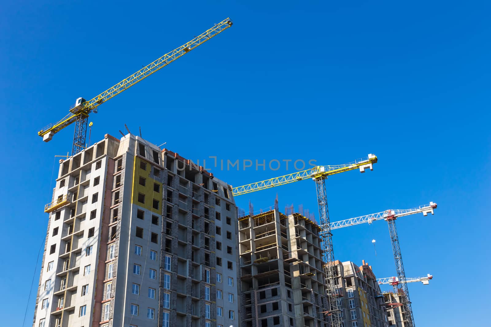 Construction cranes on building site on sky background