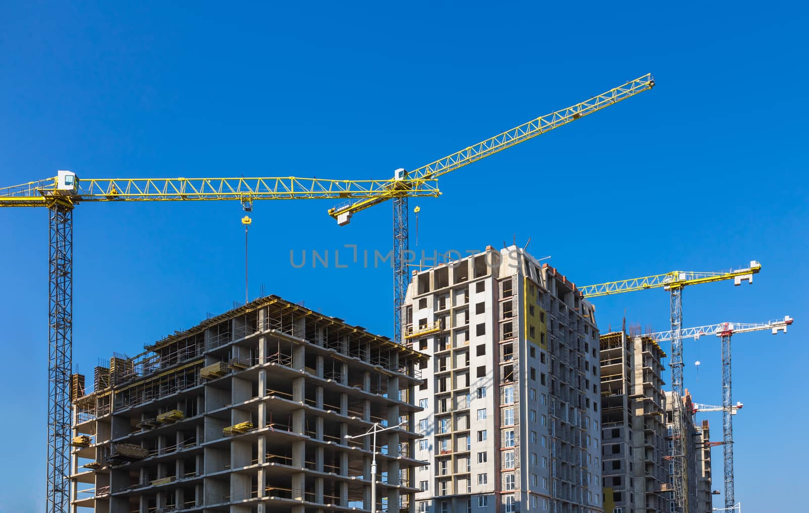 Construction cranes on building site on sky background