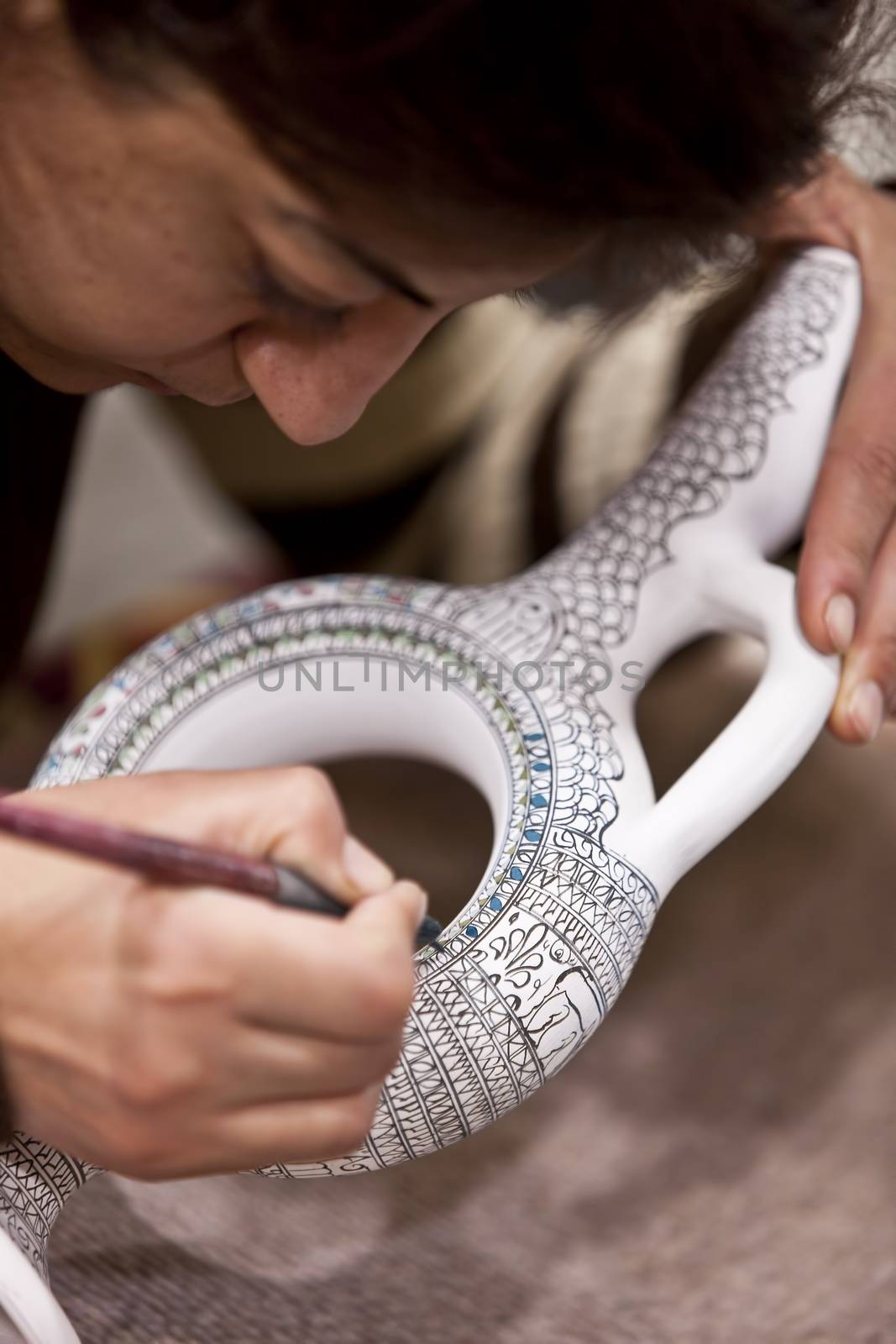 CAPPADOCIA, TURKEY – APRIL 17: Woman adds color to a ceramic vase with designs typical to the region on April 17, 2012 in Cappadocia, Turkey.