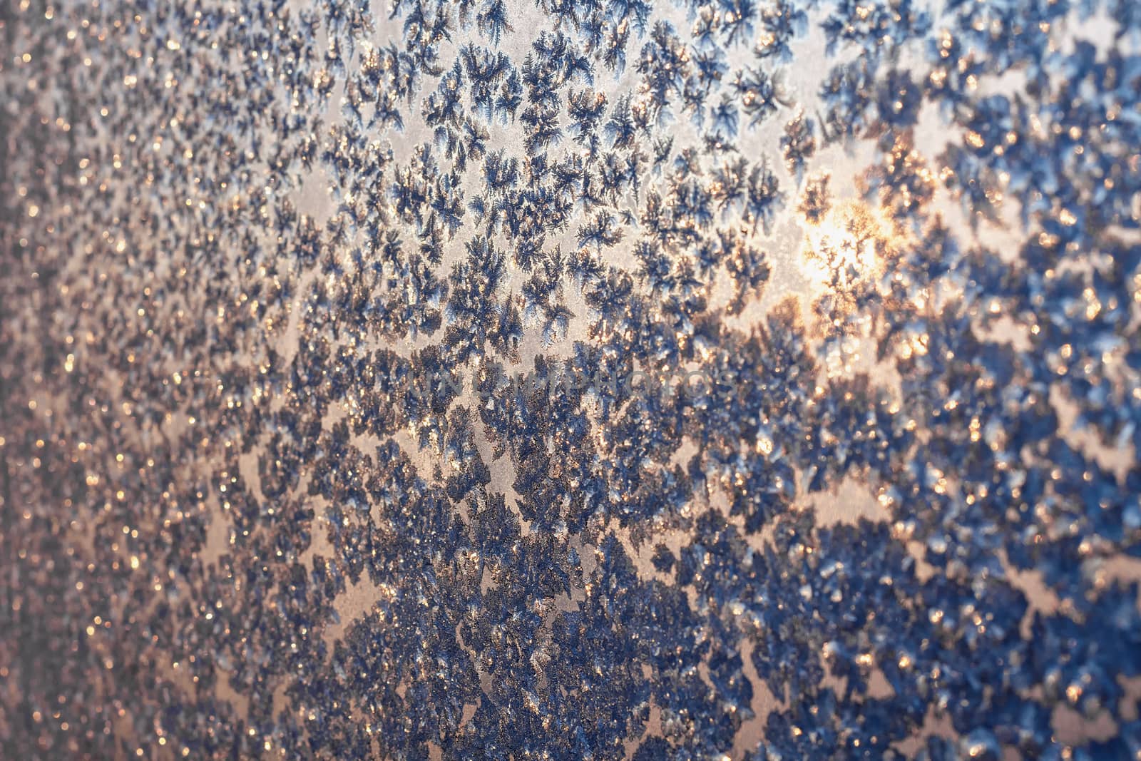 Ice snowflakes and frost over the sun on christmas winter frozen window. Natural color. Selective focus with blur edges of image