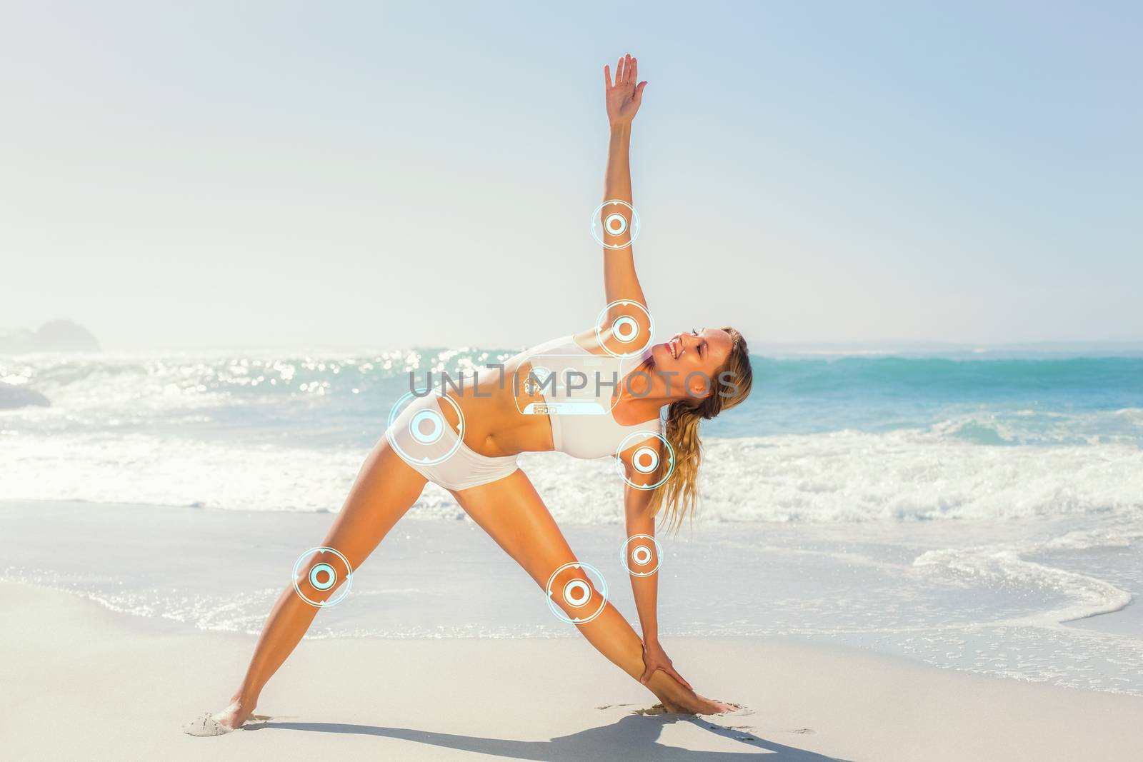 Gorgeous blonde standing in extended triangle pose by the sea against fitness interface