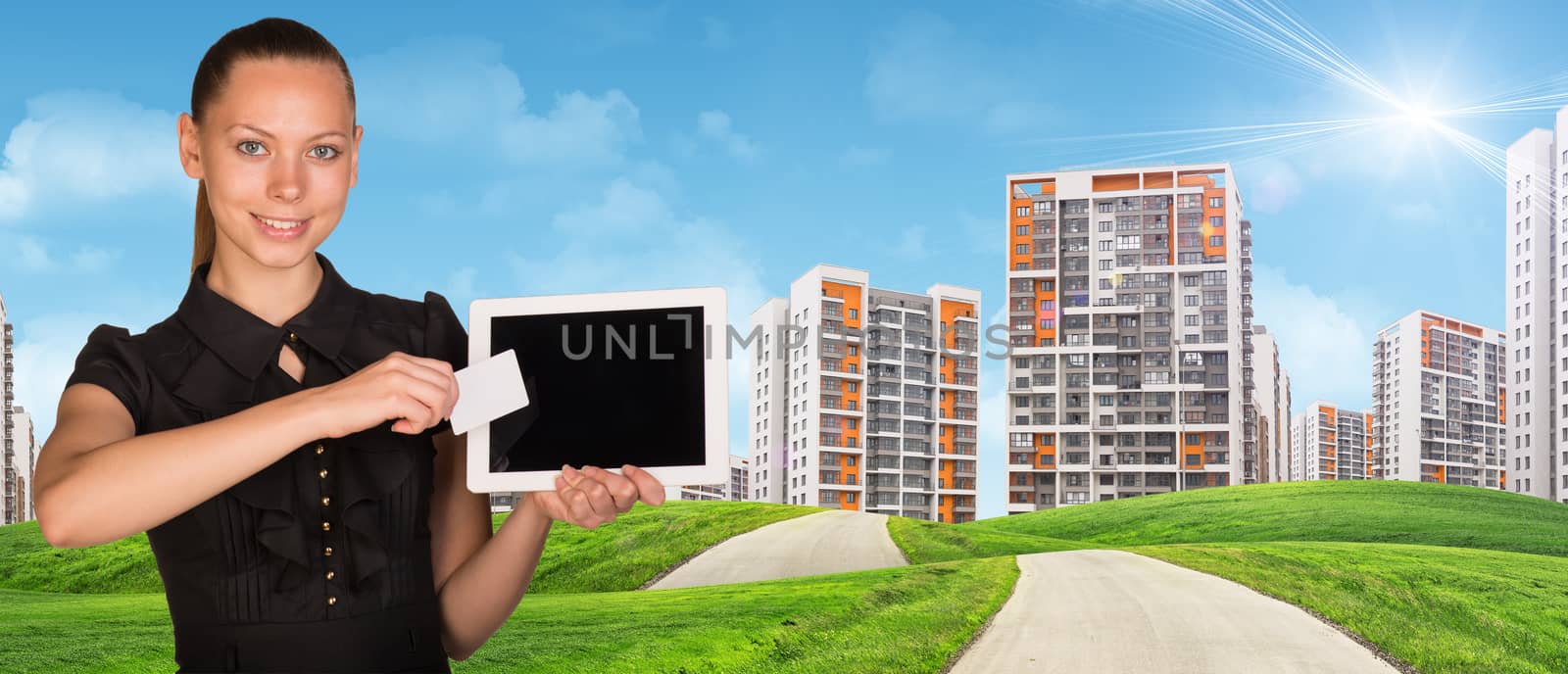 Smiling young woman holging tablet and blank card and looking at camera on cityscape under blue sky background