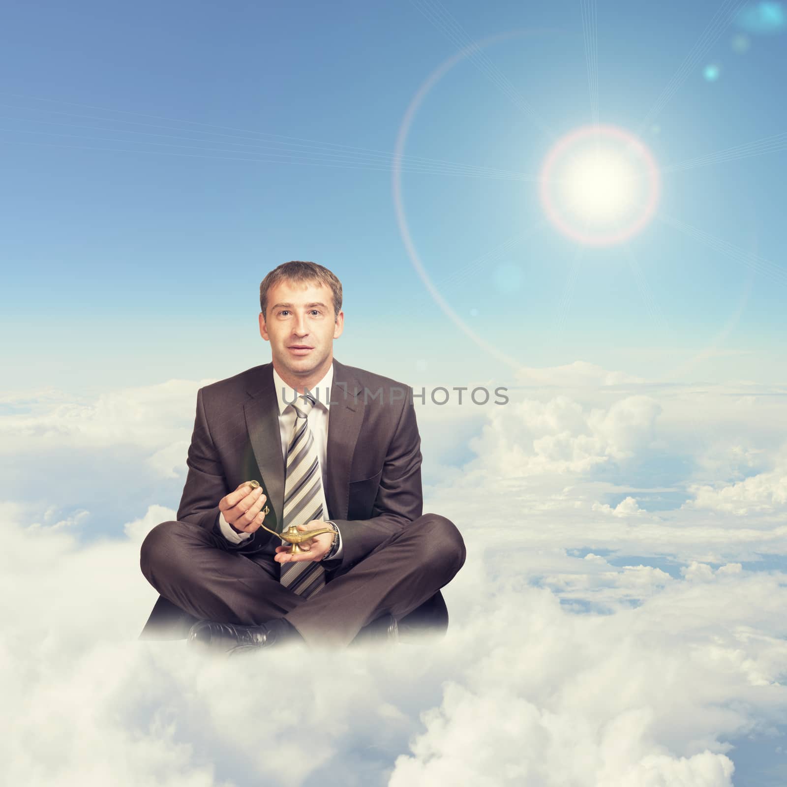 Businessman sitting in lotus position on cloud, holding oil lamp and looking at camera