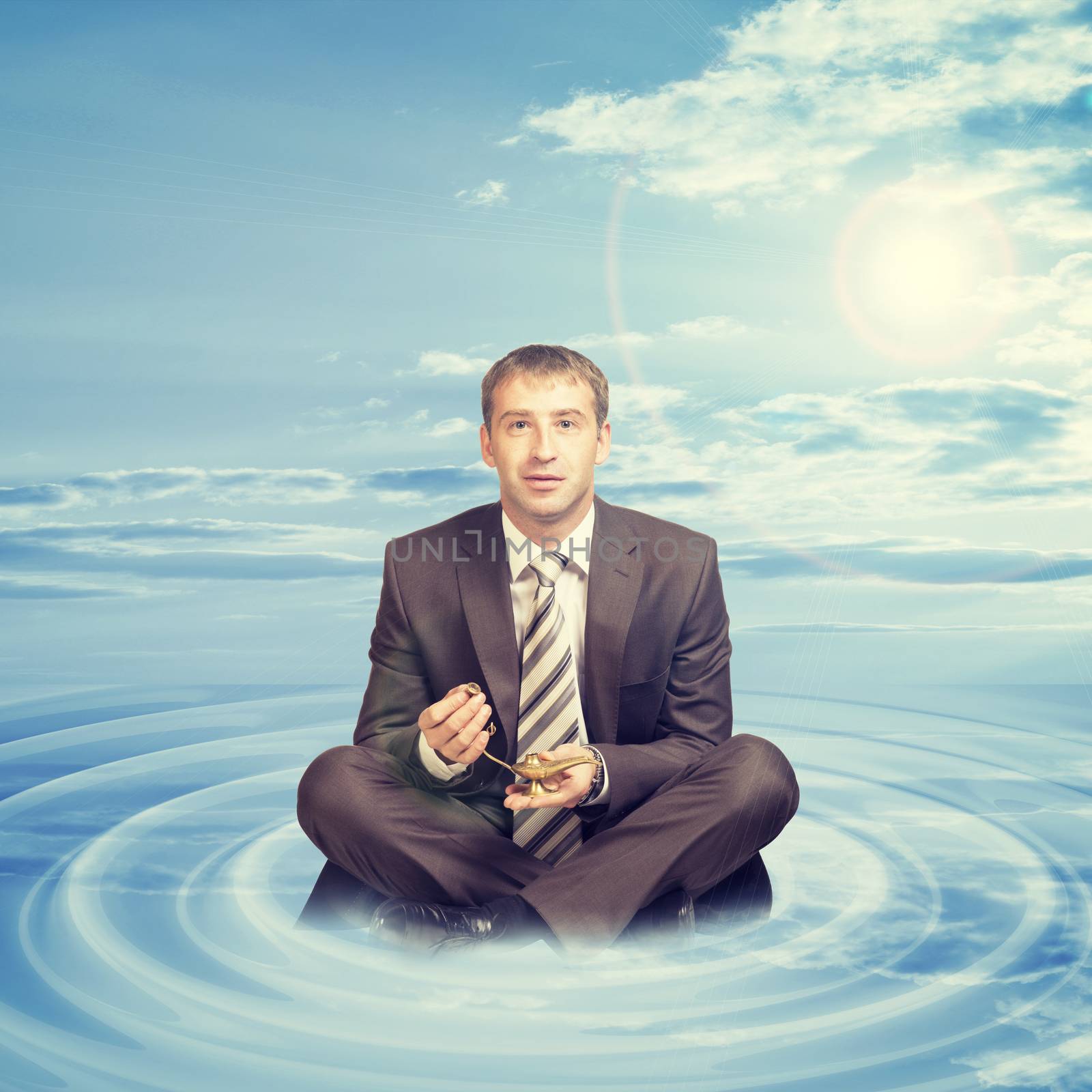 Businessman sitting in lotus position on cloud with oil lamp and looking at camera