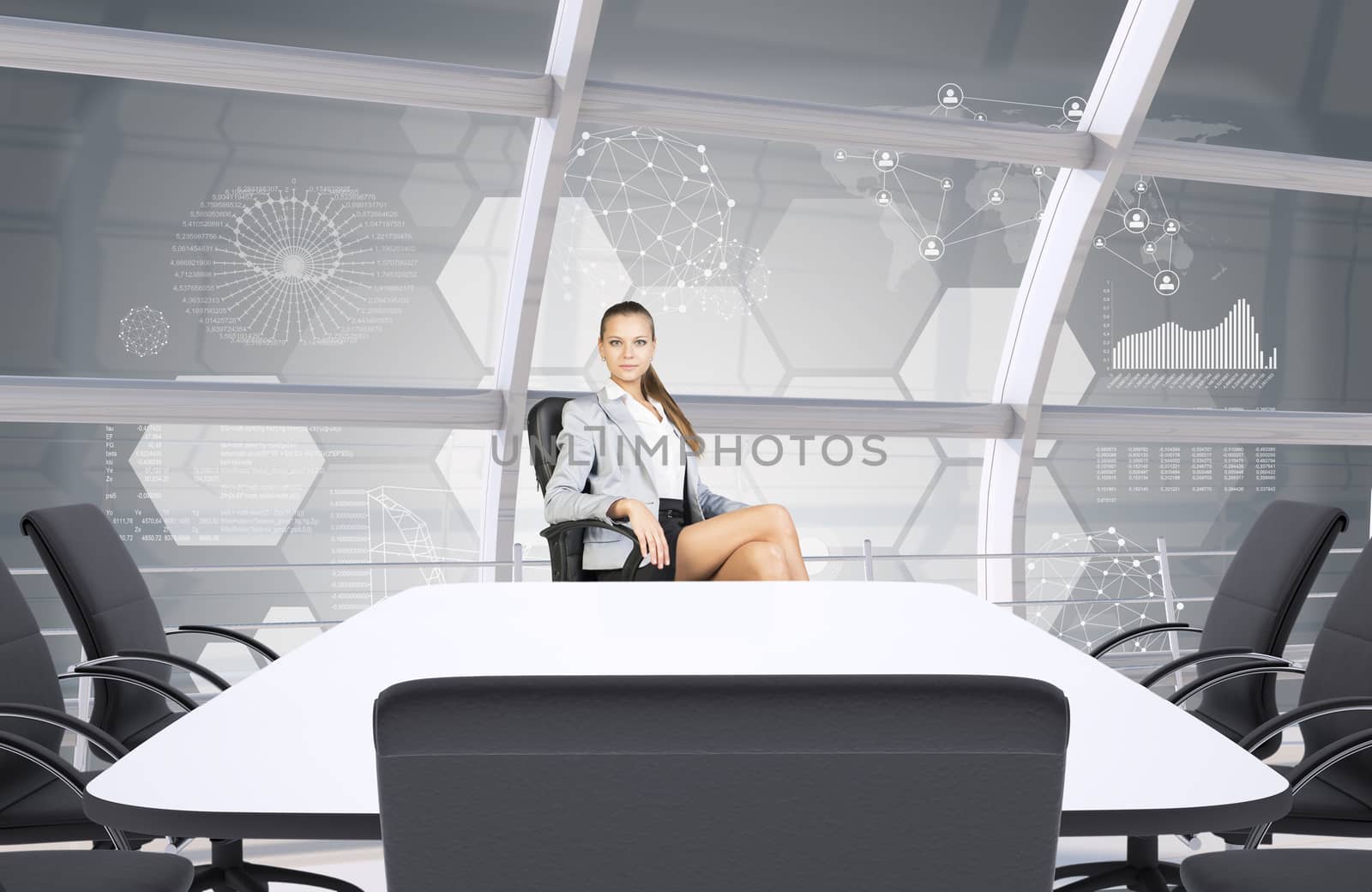 Businesslady sitting half-turned at table and looking at camera on abstract background 