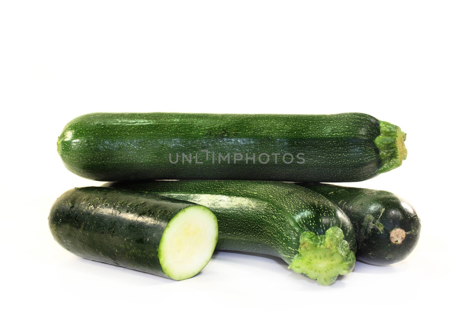 green, raw zucchini in front of white background