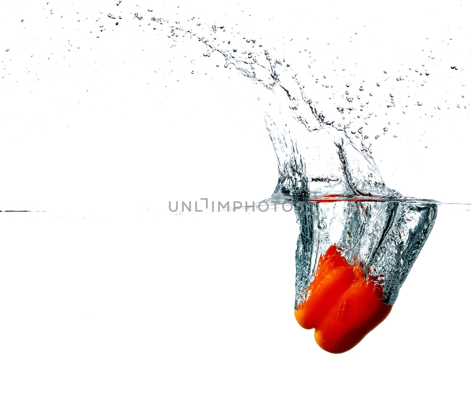 Fresh red pepper drops into a water, isolated on white background