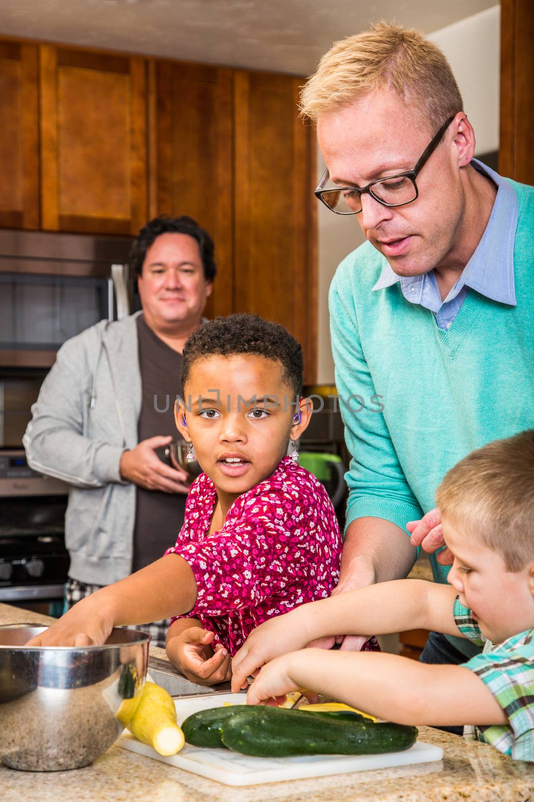 Two dads in kitchen cook with children