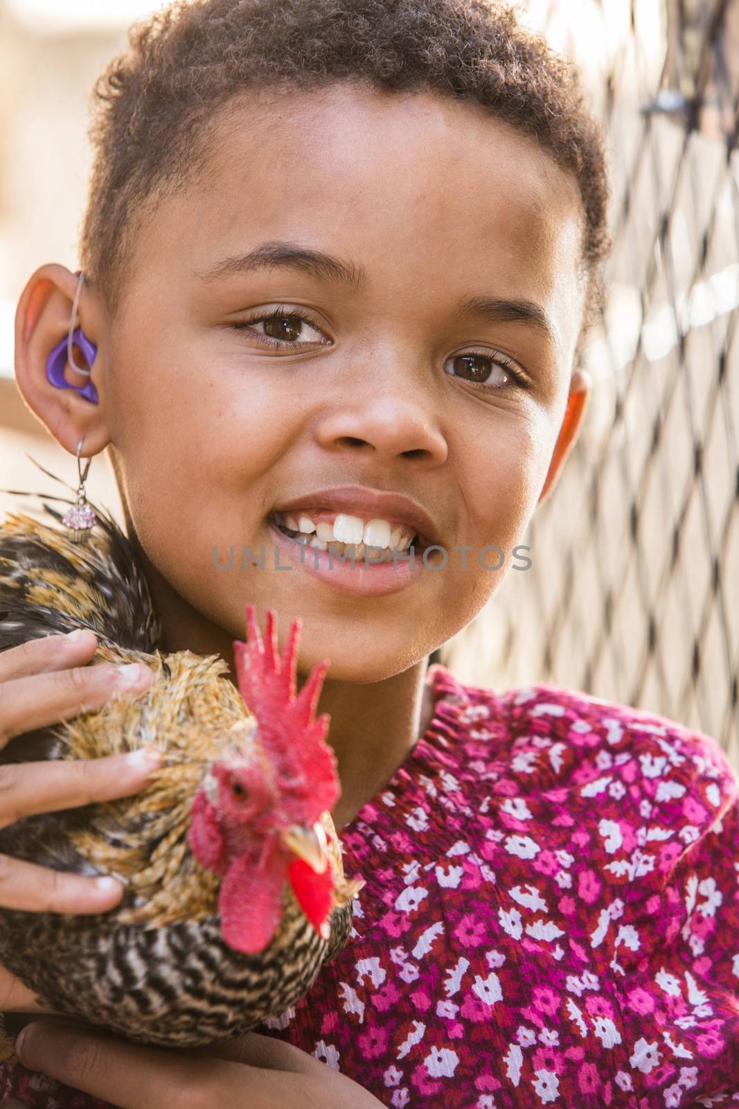 Cute African girl with hearing aid holding a rooster