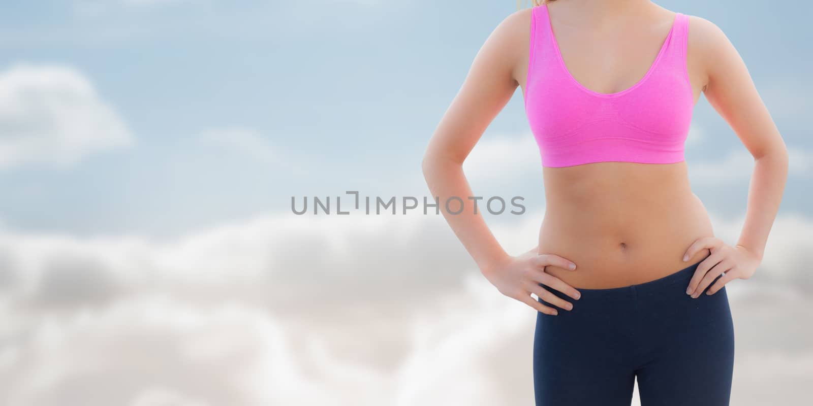 Composite image of toned woman with hands on hips on beach by Wavebreakmedia
