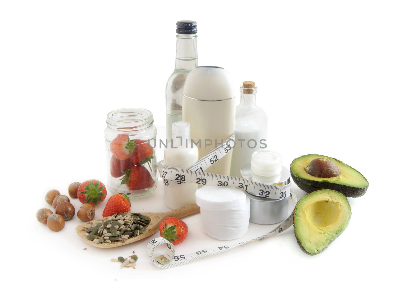 Beauty cosmetic products surrounded by various healthy for the skin foods including strawberries, pumpkin seeds and avocado