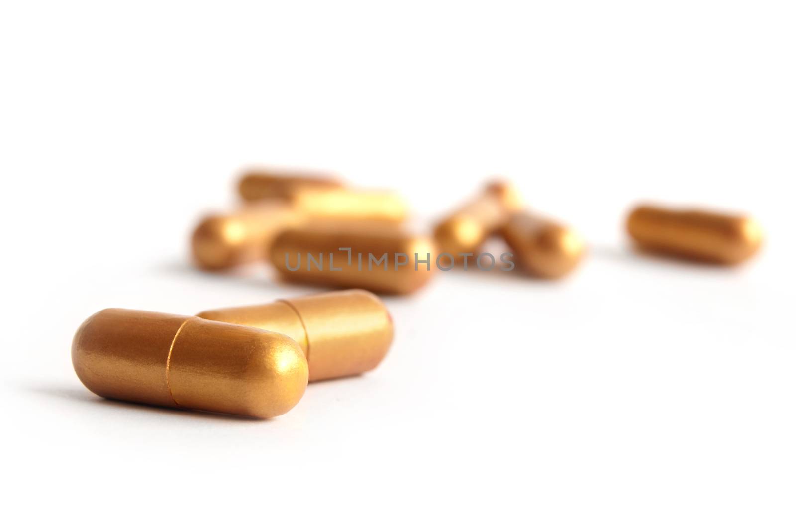 Golden medical capsules over a white background