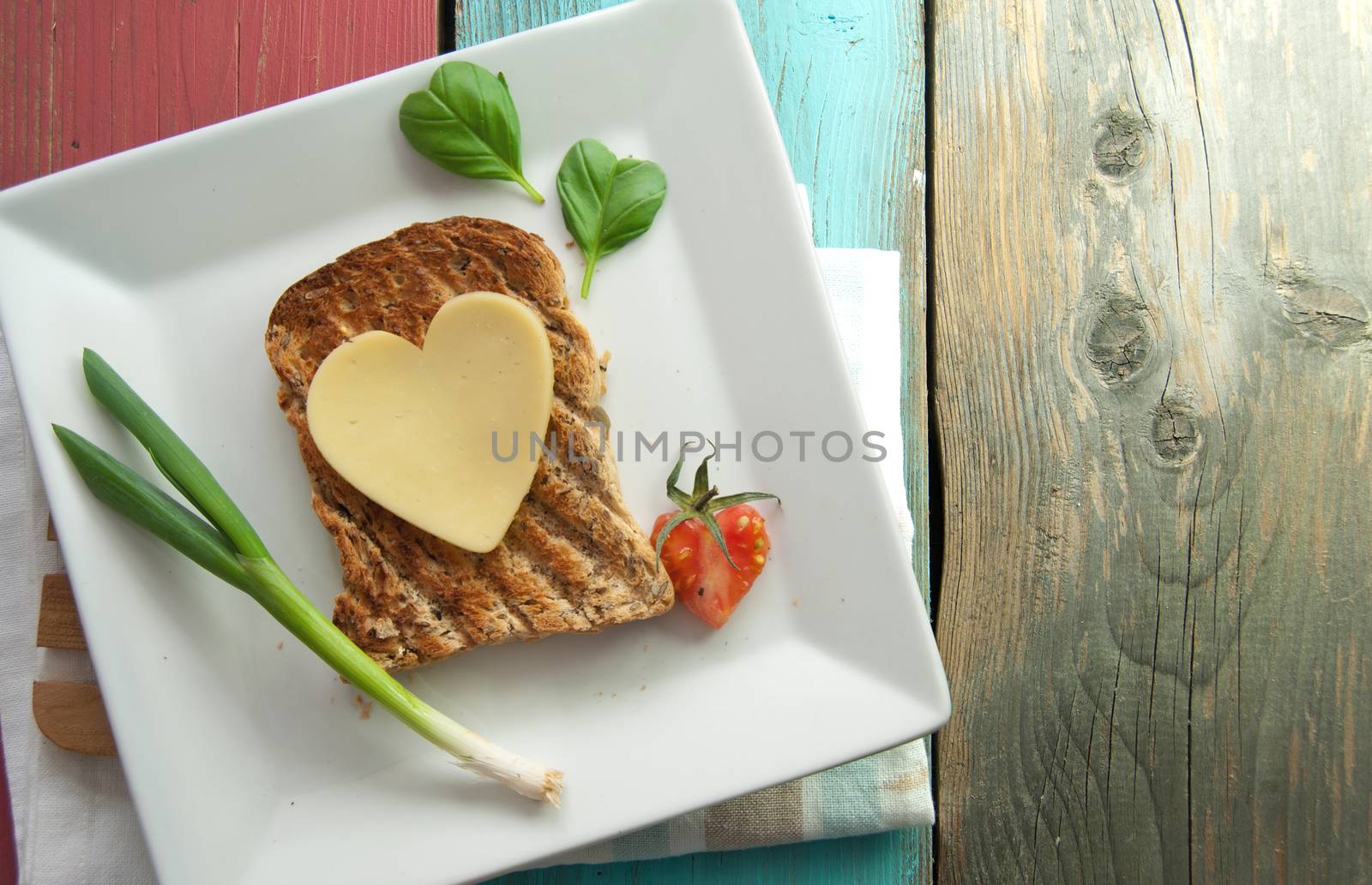 Heart shape slice of cheese on toasted whole grain bread