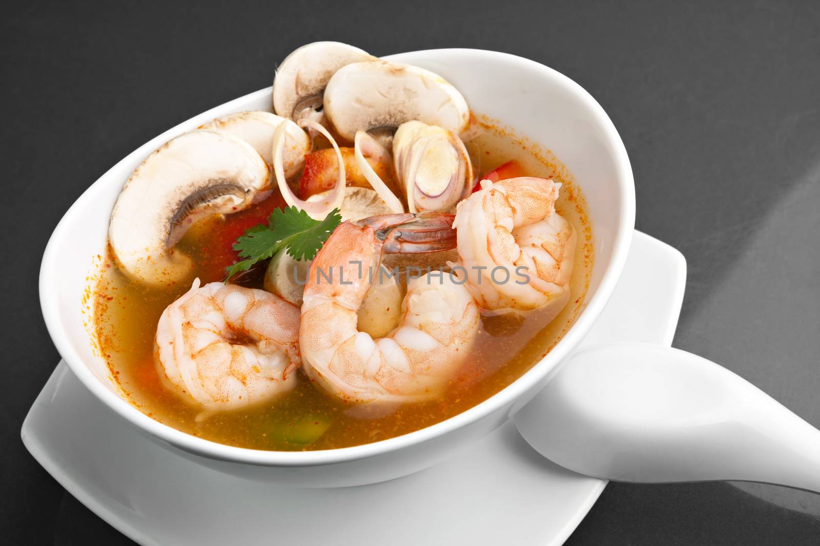 Thai shrimp soup bowl close up with mushrooms and vegetables.