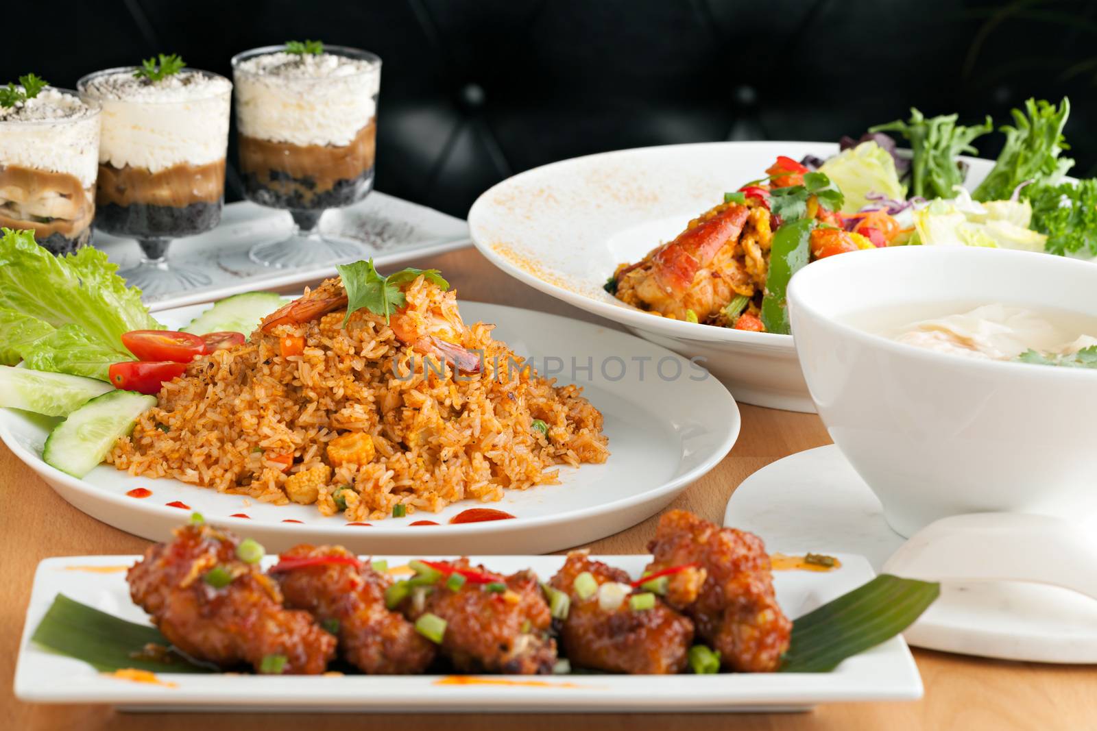 Varieties of Thai foods and appetizers covering a table. Shallow depth of field.