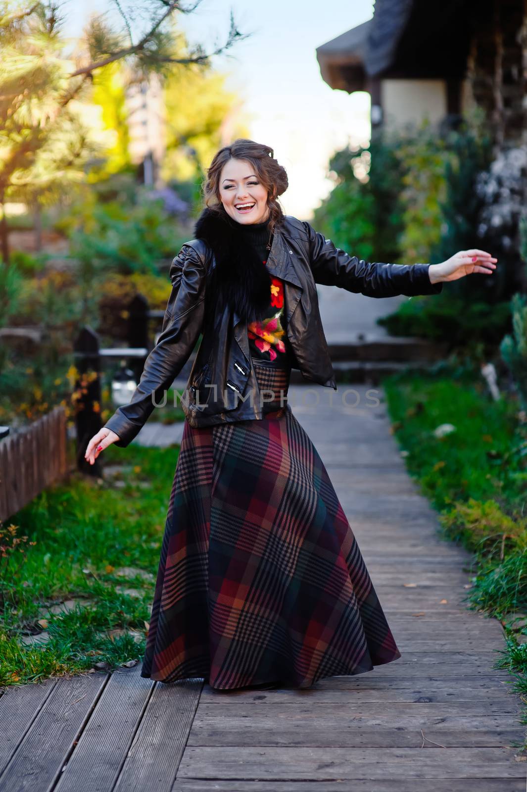 Beautiful girl in a black jacket near wooden house.