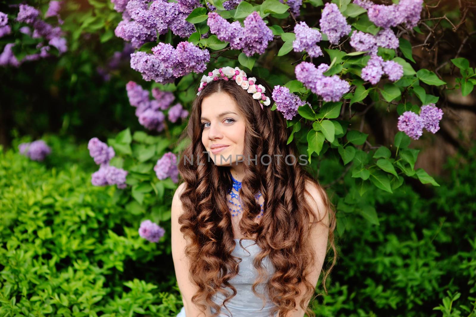 Beautiful young woman in lilac flowers, outdoors portrait.