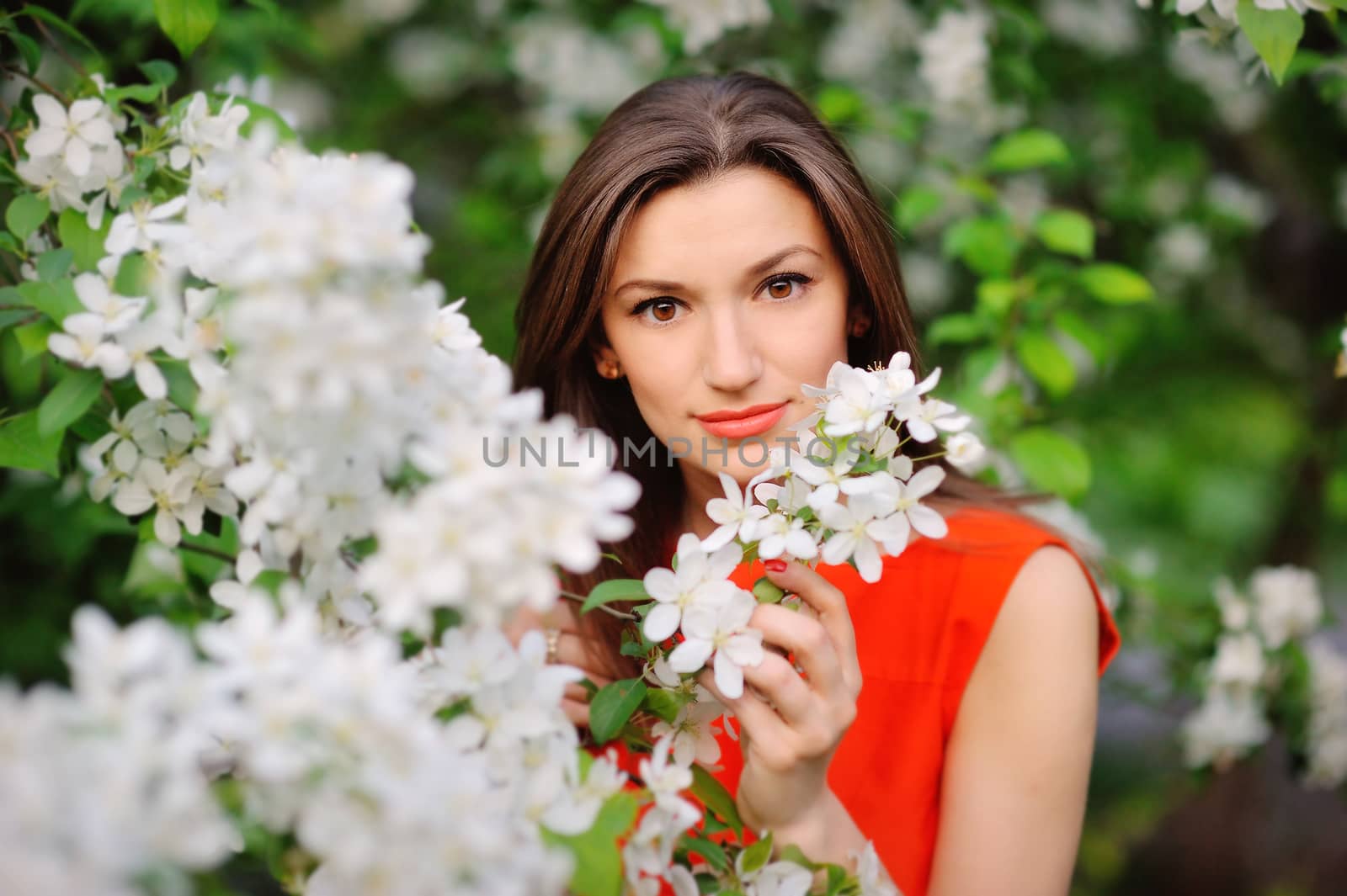 Portrait of brunette girl on a background of flowering trees.