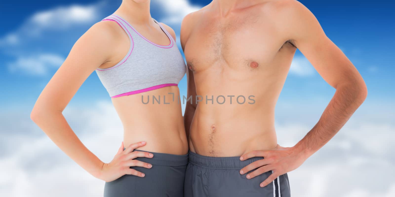 Mid section of a fit young couple against bright blue sky with clouds