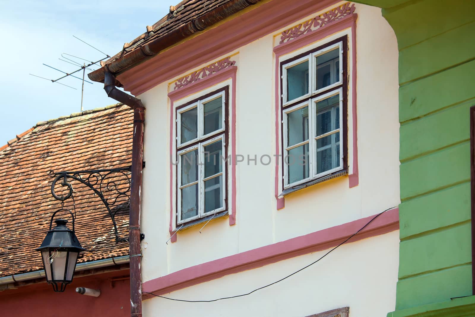 Turda, Romania - June 23, 2013: Pink facade with white windows and street lamp on an old pink house from the Old Turda city center, Romania