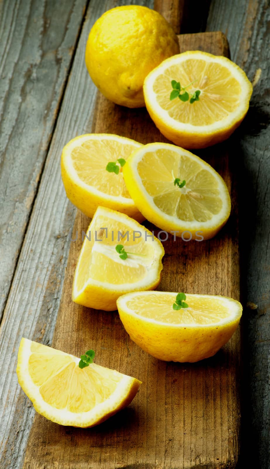 Ripe Raw Lemons Full Body and Halves on Wooden Cutting Board on Rustic background