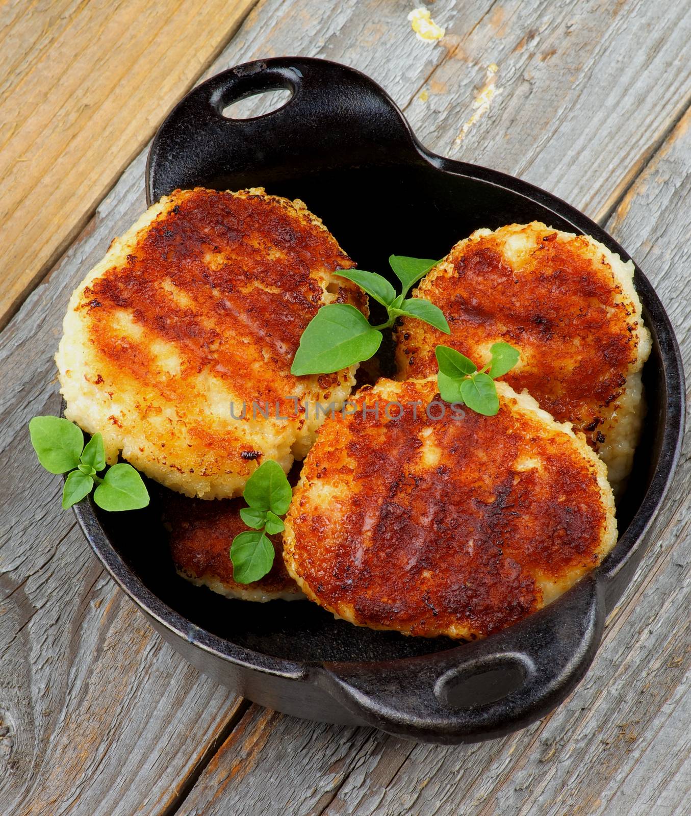 Delicious Homemade Meat Cutlets in Black Saucepan with Basil closeup on Rustic Wooden background